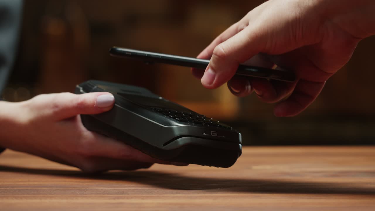 Paying with smartphone close-up. Cashless shopping in restaurant or cafe. Touch-free and contactless payment concept. NFC technology and bank terminal.