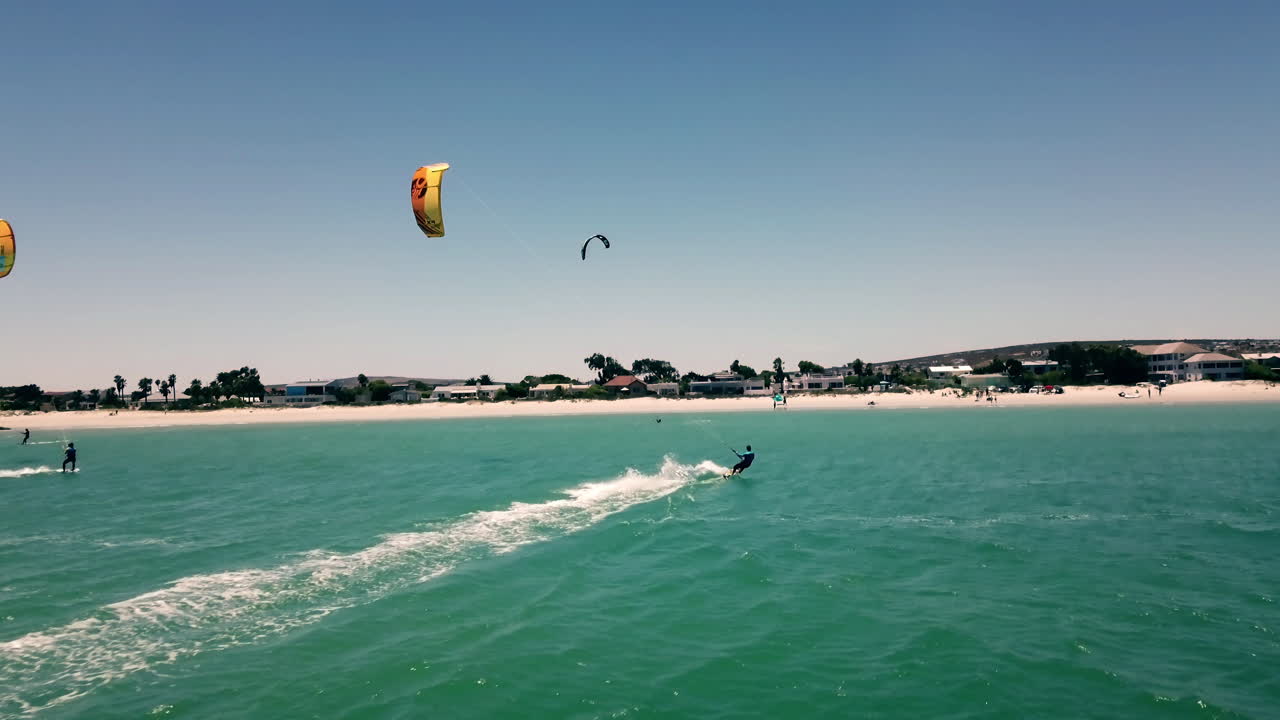 밝고 화창한 날 남아프리카 랑게바안 해변에 접근하는 전체 돛에 카이트 서퍼의 아름다운 픽업 샷