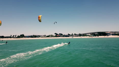 beautiful pickup shot of kite surfers in full sails approaching langebaan beach, south africa on a bright sunny day