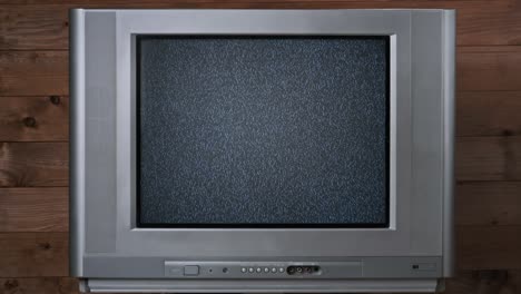ruido estático en la pantalla de un viejo televisor de crt sobre fondo de madera, sin señal