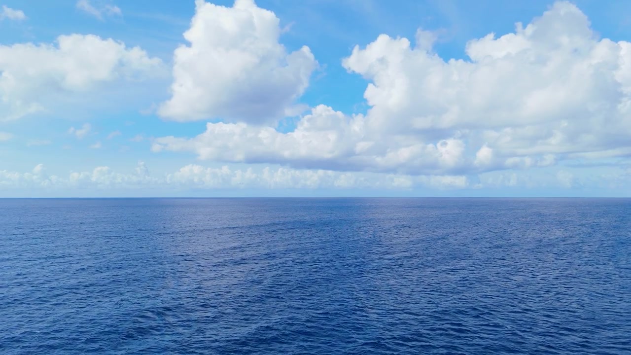 Delicata carrellata aerea di un vasto oceano blu sotto un cielo sereno, superficie del mare calma e pacifica