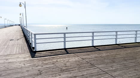 long wooden pier extending into the calm sea under a clear sky