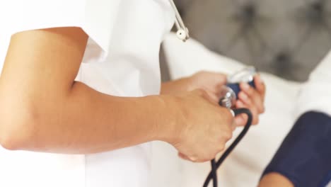 female doctor measuring blood pressure of mature woman in bedroom 4k