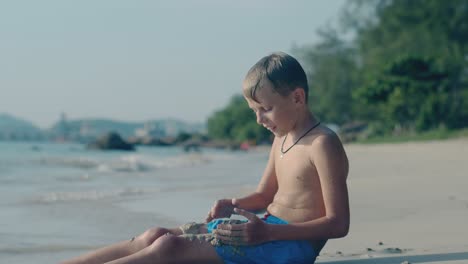 happy boy plays with wet sand on empty tropical beach