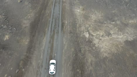 aerial drone shot following a car driving off road in iceland.  vertical view