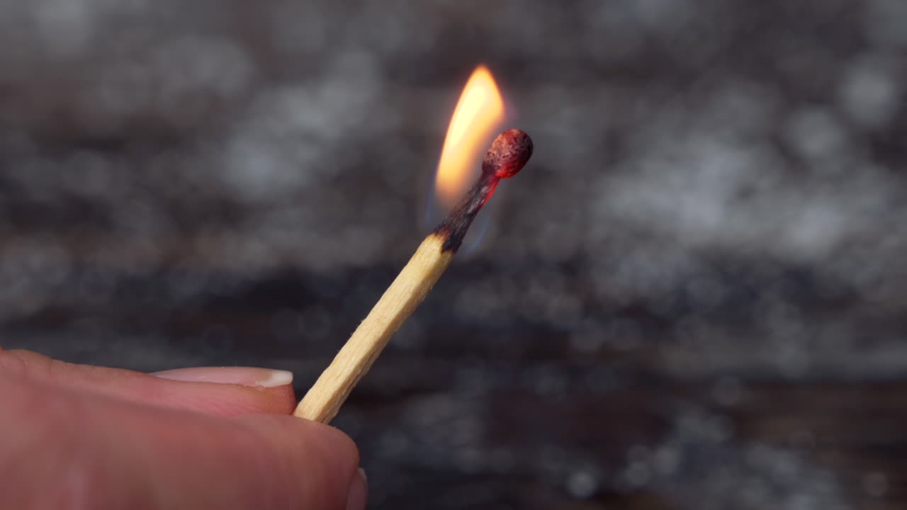Close up of a woman holding a burning match