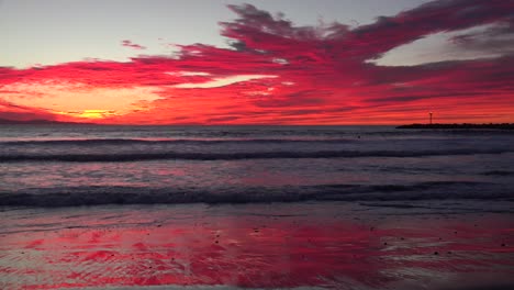 a blood red sunset illuminates a southern california beach