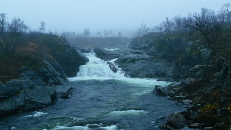 small waterfall in foggy landscape