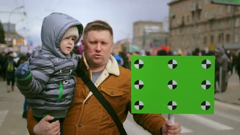 single father with son at rally. dad with empty mockup sign at demonstration.