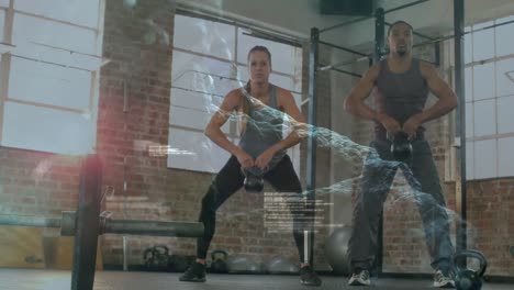 procesamiento de datos médicos contra una pareja de raza mixta que hace ejercicio con kettlebells en el gimnasio