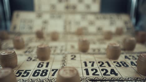 a vertical macro video of a bingo board, studio lights, 120 fps, super slow motion, wooden chip digits, raw footage, vintage lottery desk game, card numbers, crane smooth movement