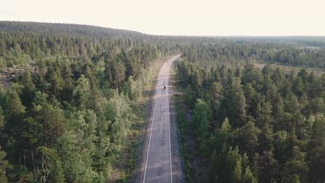 Un-Dron-Disparó-Sobre-Un-Motociclista-Que-Circulaba-Por-Una-Carretera-Dentro-De-Un-Bosque-En-El-Norte-De-Finlandia,-Europa,-Por-Encima-Del-Círculo-Polar-ártico