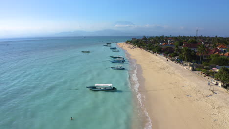 Bali---has-most-beautiful-beaches-in-Indonesia,-drone-footage-in-4k-filmed-volcano-Agung-in-distance,-stunning-white-sand-beach-and-blue-ocean-view-with-sailing-boats-waiting-for-fisherman