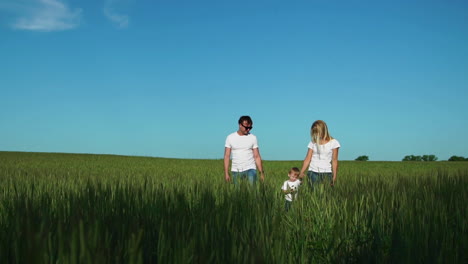 Mom-father-and-son-go-to-the-field-with-a-football-against-the-blue-sky