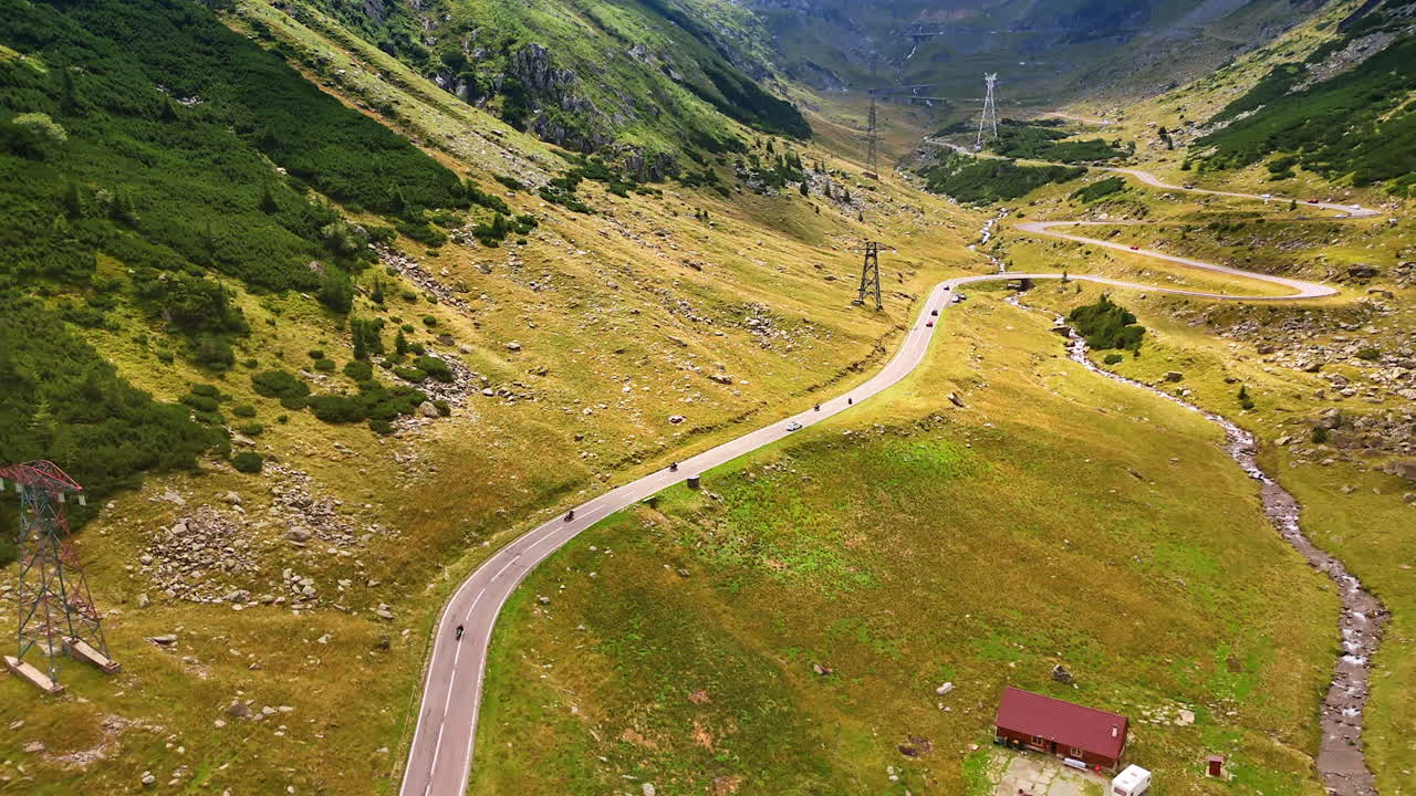 Cars and motorcycles move by the wavy highway in the mountains. Drone footage above the stunning dangerous Transfagarash highway in Romania