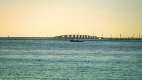 fishing boat cruising in front of the seven mile bridge at sunset in the florida keys