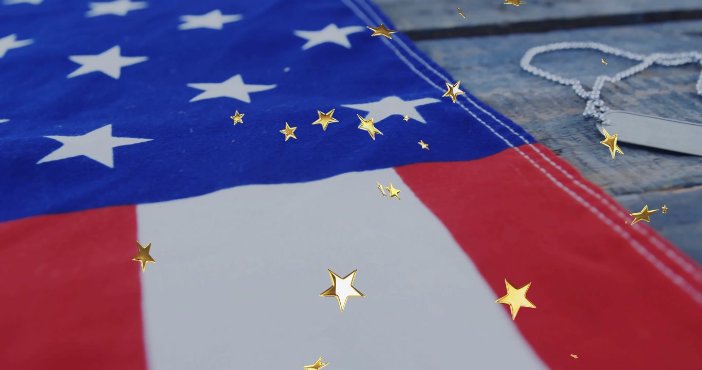 Gold star confetti drifting across US flag then view panning revealing dog tags, honoring service