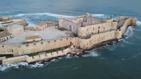 low aerial of the castle and lighthouse of syracuse in the mediterranean sea