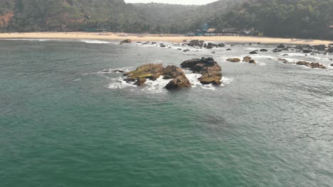 coastal eroded rocks near shoreline in arambol, in goa, india - aerial crane down tilt up reveal