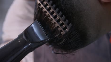 peine de cepillo negro y secador de cabello negro utilizado para peinar enderezar el cabello negro en la parte superior de la cabeza negra por barbero, filmado en primer plano disparado en estilo de cámara lenta vertical de mano