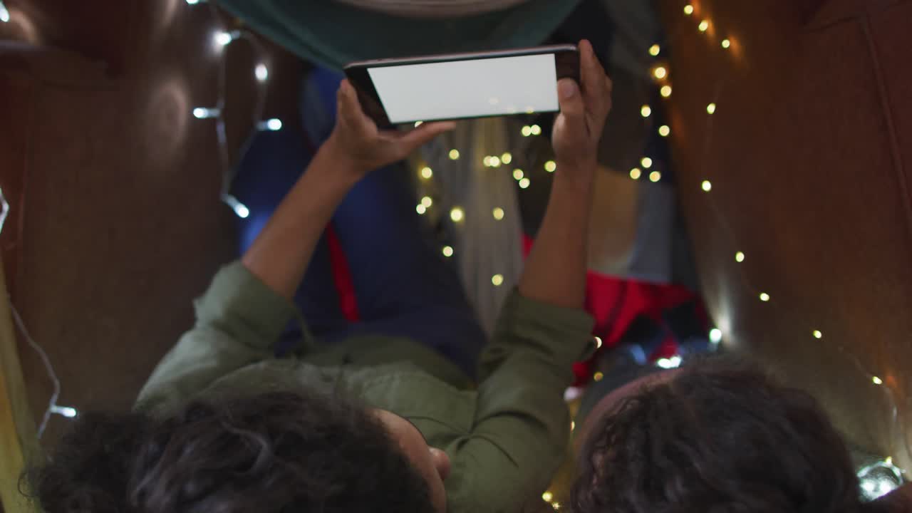 madre e hija de raza mixta usando una tableta en una tienda de campaña