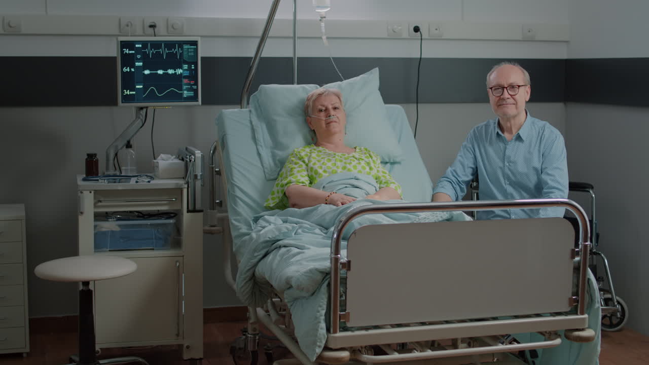 Portrait of aged patient and man sitting in hospital ward