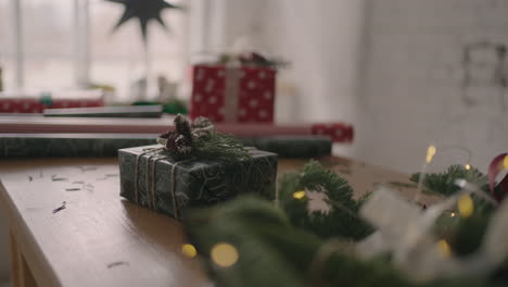 A-Christmas-present-stands-on-a-wooden-table-with-Christmas-trees-and-garlands.-Beautiful-Christmas-gift