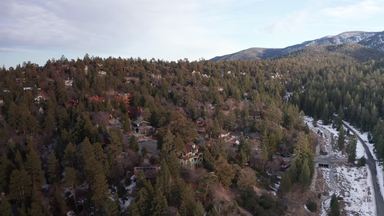 retirada aérea inversa de una gran cabaña con vistas al bosque alpino durante el invierno en big bear lake, california