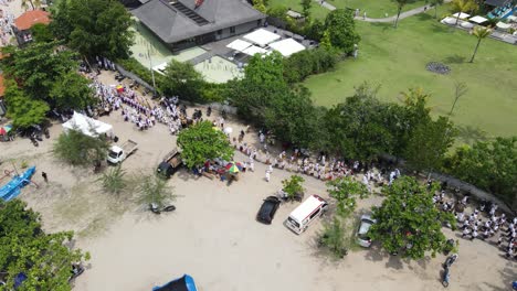 Aerial-view,-procession-on-Samuh-beach-during-the-Melasti-ceremony-before-the-silent-day-of-Nyepi