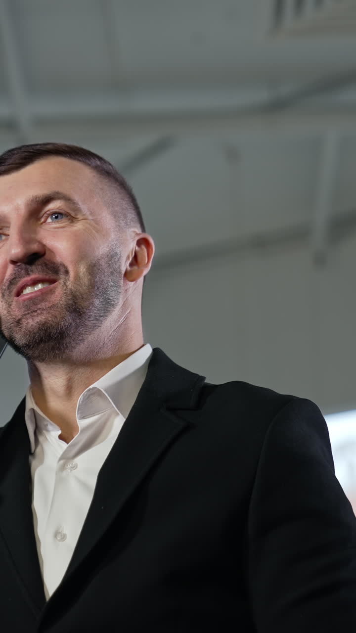 Entrepreneur in suit speaking on the smartphone and smiling. Business phone call and discussing work issues. View from below. Vertical video