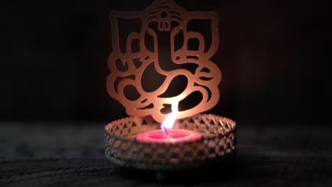 tilt up closeup to a ganesha cutout with tea candle, or ganapati, vinayaka, or by numerous other names, is one of the best-known and most worshipped deities in the hindu pantheon.