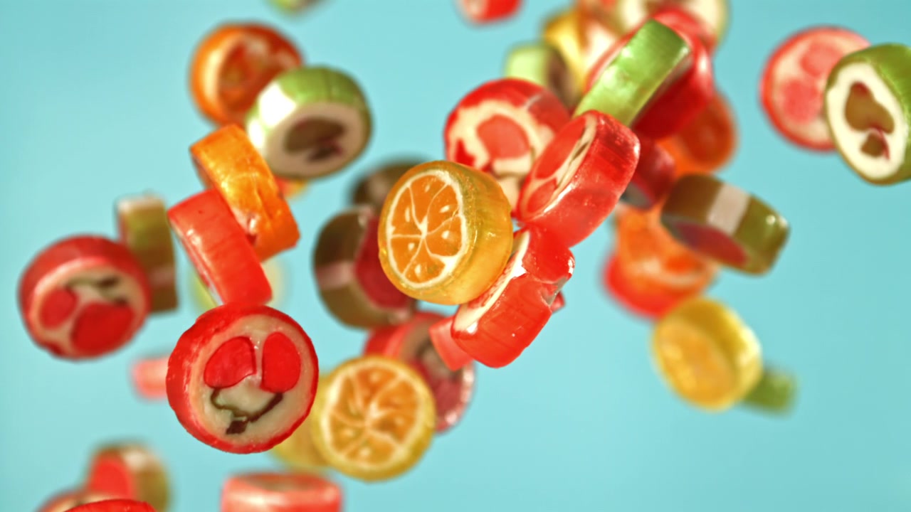 Verschiedene bunte Fruchtbonbons schweben vor blauem Hintergrund.