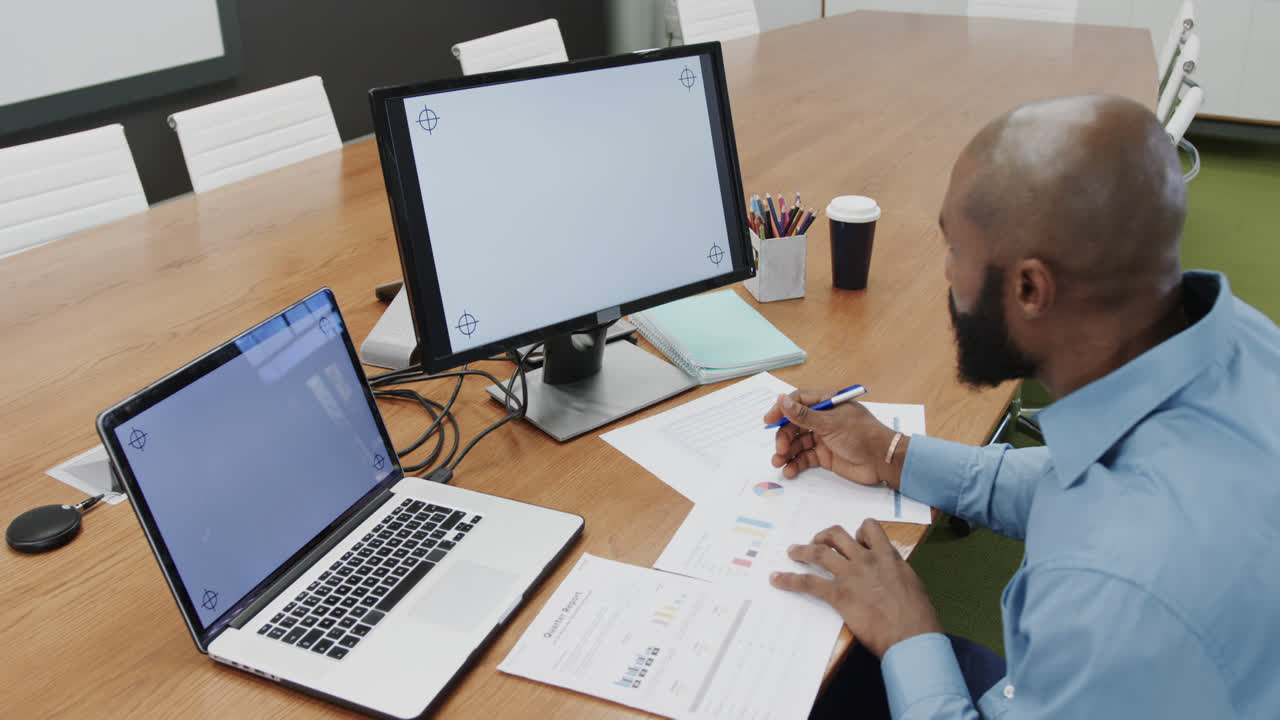 African american businessman in office using computer and laptop, copy space on screens, slow motion