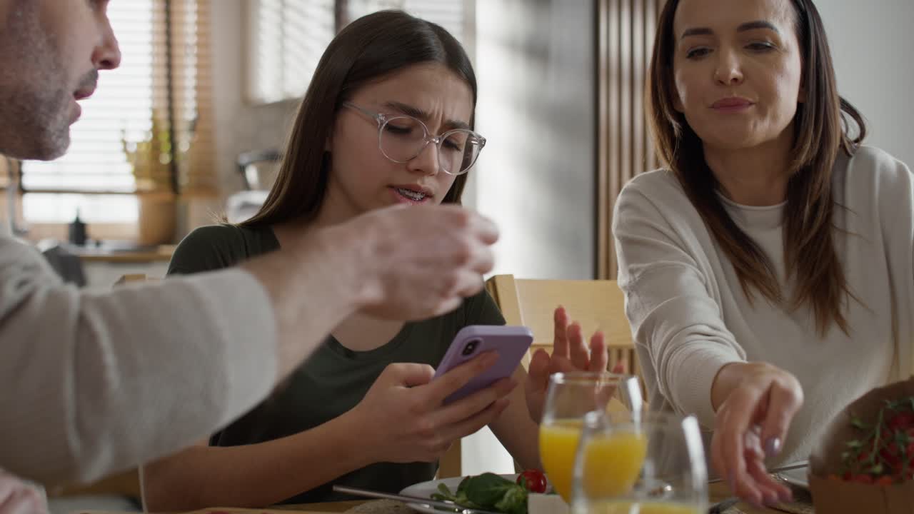 adolescente usando el teléfono móvil durante el desayuno en la mesa