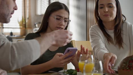 teenage girl using mobile phone during breakfast at the table