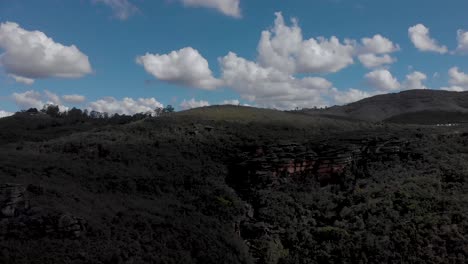 vibrant blue sky with clouds above rock plateau in the andorinhas [swallows] park near ouro preto, minas gerais, brazil. aerial ascending landscape view.