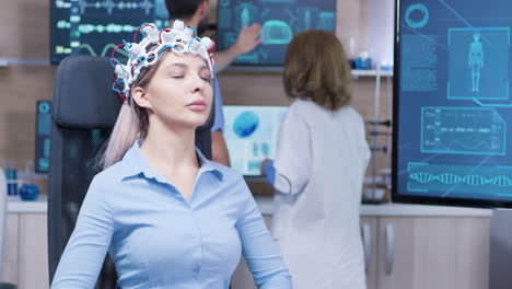 paciente femenina sentada en una silla y con sensores de actividad cerebral