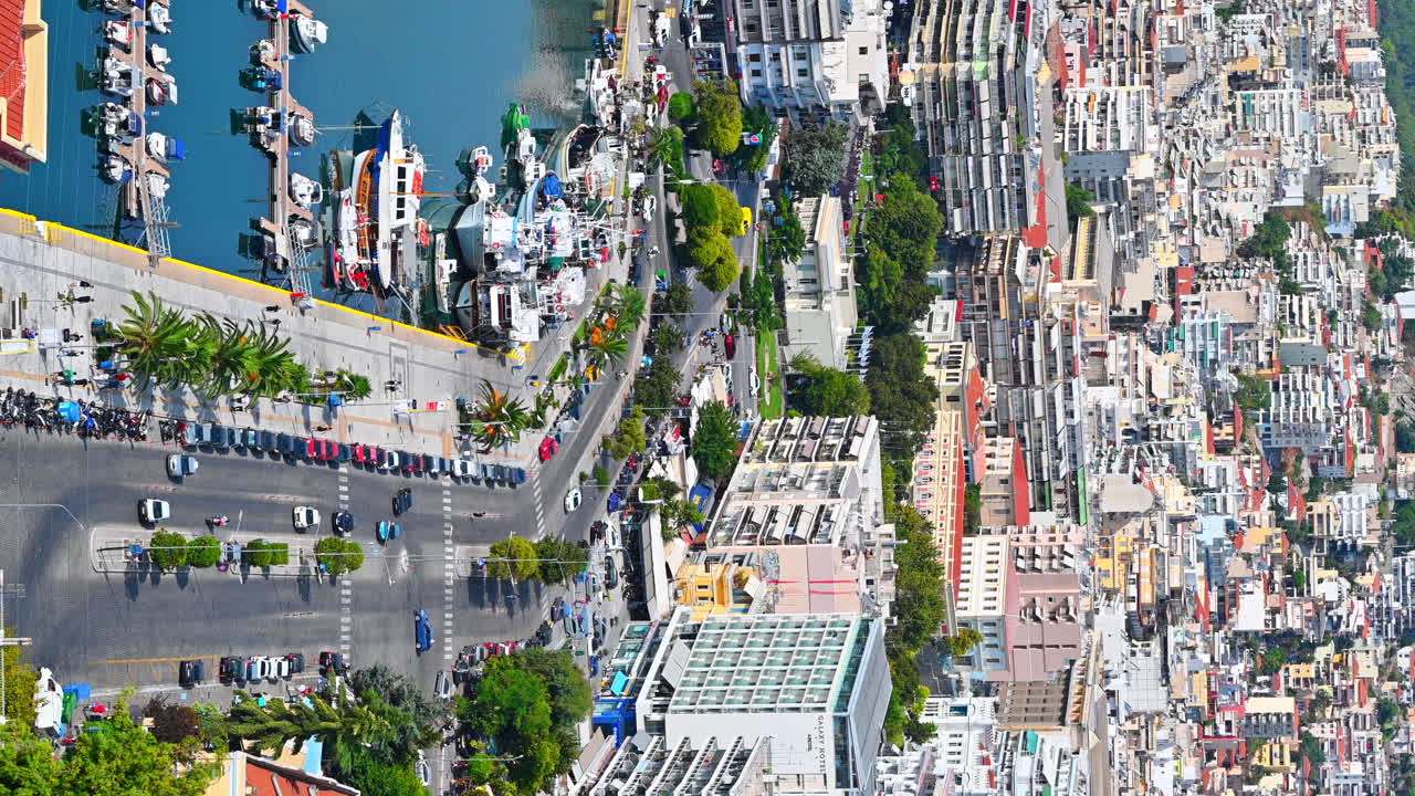 KAVALA, GREECE - SEPTEMBER 23, 2020: Aerial view of the city. Rows of residential buildings, Aegean sea port with moored yachts, roads with people and cars