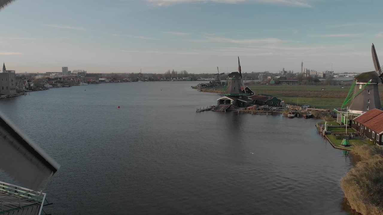 푸른 하늘이 있는 밝은 날에 회전하는 심지가 있는 전형적인 네덜란드 풍경에서 풍차를 가까이서 드러내는 풍차의 공중 전망