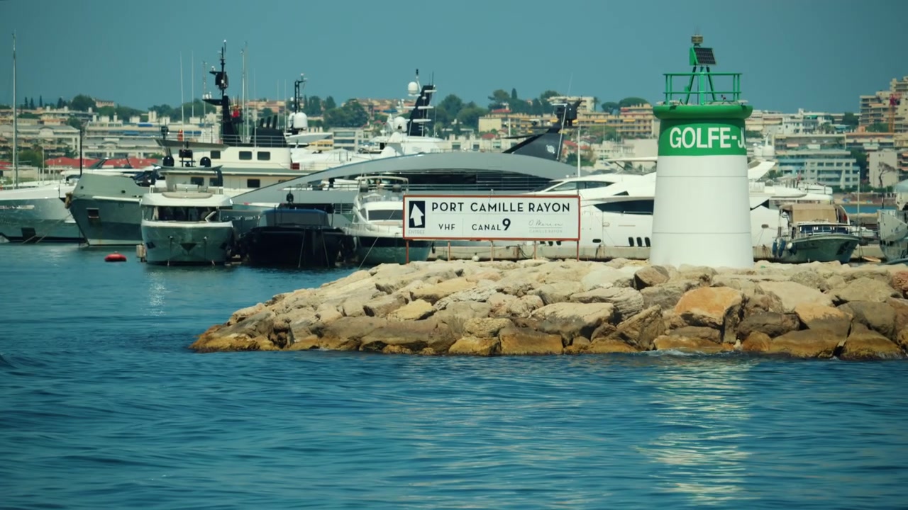 Marina Port Camille Rayon Golfe-Juan che espone yacht di lusso e un faro verde sulla costa della Costa Azzurra, Golfe Juan, Francia.