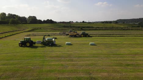 Parallel-drone-shot-of-three-tractors-working-with-hay-in-Rhenen-in-The-Netherlands