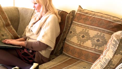 Peaceful-woman-sitting-on-sofa-using-a-laptop