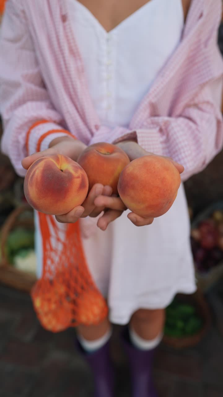 Femme tenant des pêches dans un marché de producteurs