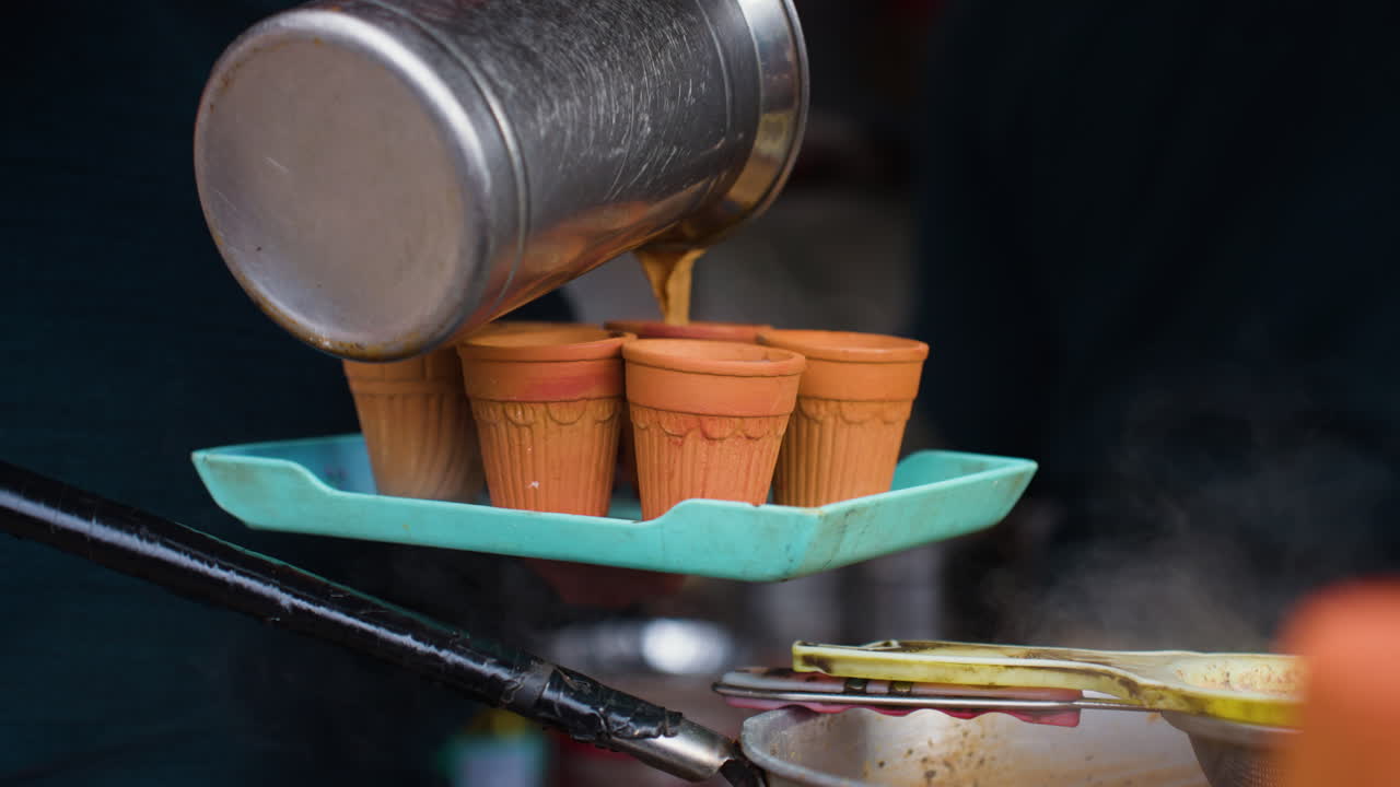 Venditore ambulante che versa tè chai Masala Nainital caldo fumante in tradizionali tazze di terracotta Kulhad.
