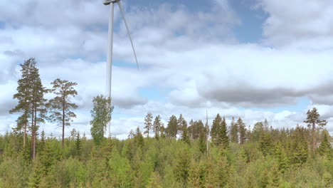 alta turbina eólica en el bosque gira contra el cielo nublado