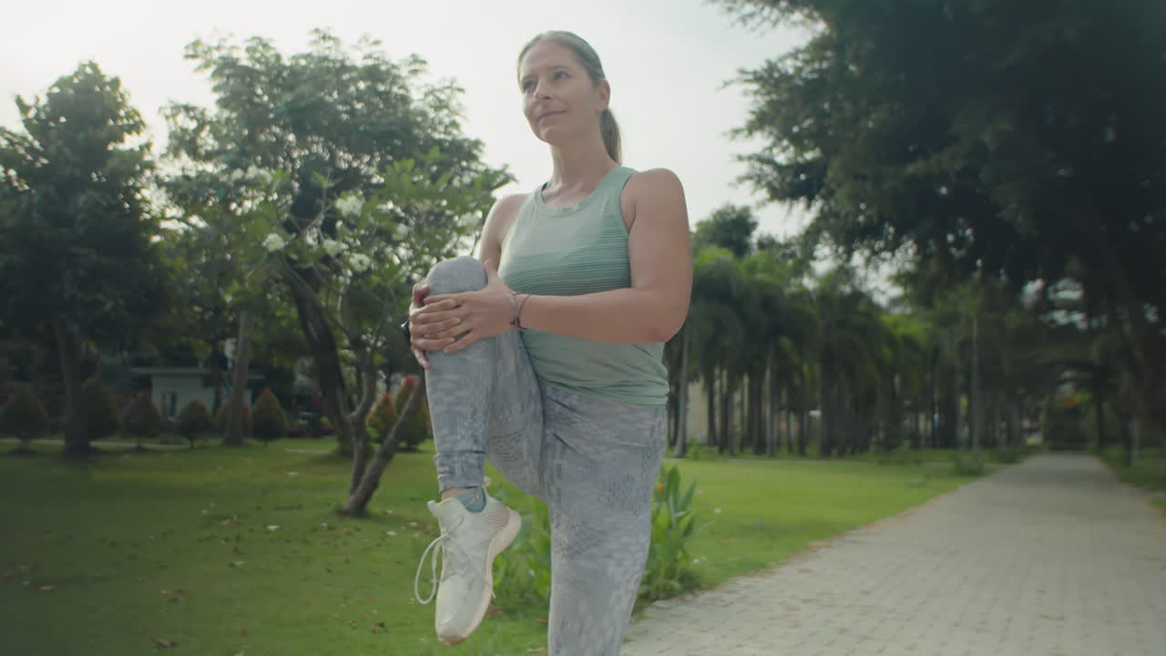 Athletic Woman Stretching Legs before Run in Park