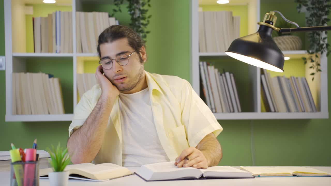 책 보는 것에 지루한 젊은 남성 학생.