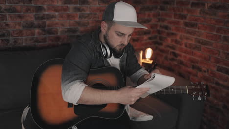 young modern musician man creating music, having ideas, taking notes at home