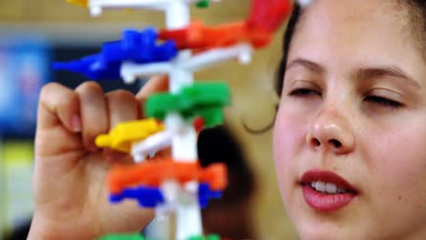 schoolgirl experimenting molecule model in laboratory at school