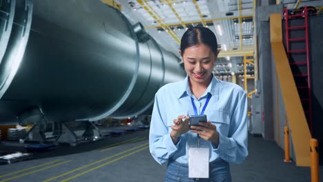 an asian business woman using mobile phone in pipe manufacturing factory